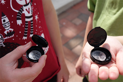A pair of children examine their new coins.