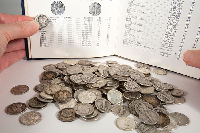 A collector looks up the value of a Mercury Dime. Image: Adobe Stock.