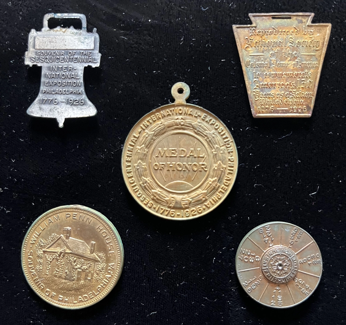 This is an image of an assortment of medals and pins issued to commemorate the 1926 Centennial. 