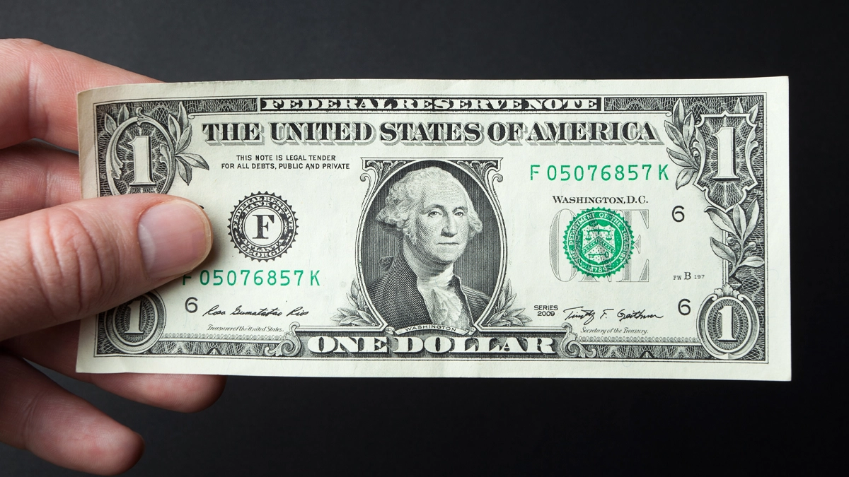 An image of a man holding a one dollar bill.