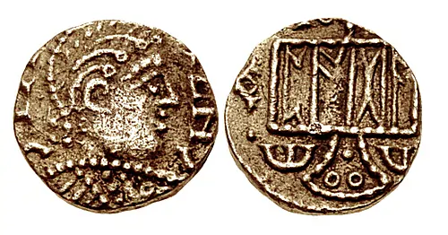 Pale gold Thrymsa (11.5mm, 1.25 g,). 'Pada' series Mint in Kent. Circa 660-675. Helmeted bust right; annulets flanking helmet, CTΛ ZNC (C's retrograde) clockwise around from lower left / Standard inscribed PADA (in Runic); North 151;