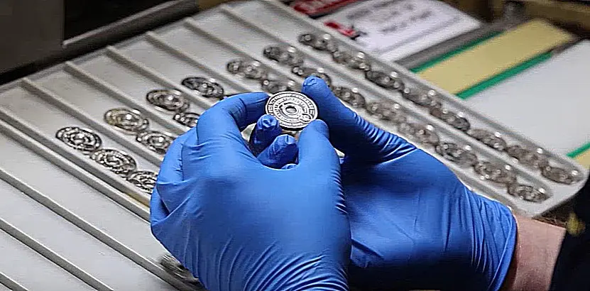 At the Royal Australian Mint a woker inspects the "Holey Dollar" as it comes off the press.