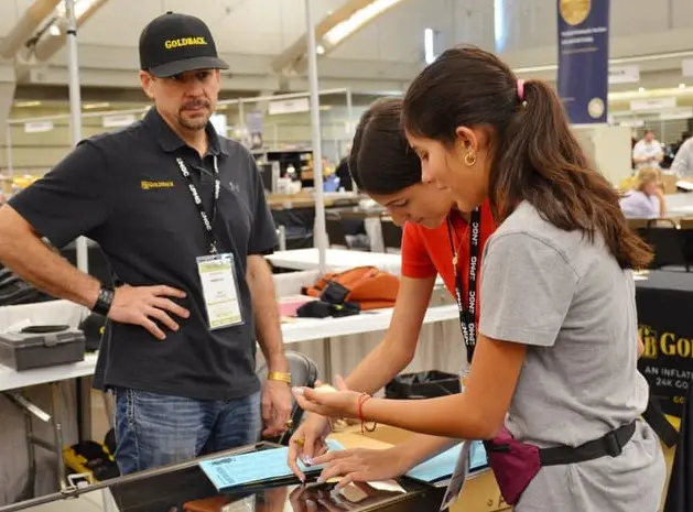 Two young collectors participating in Treasure Trivia receive a prize at the Goldback table.